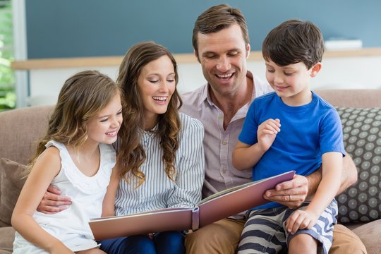 Family sitting on couch looking at photo album 