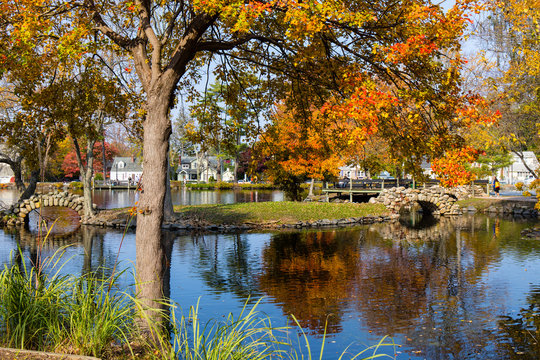 A colorful scene of a park with a tress and a pond in autumn. Heckscher Park, Huntington, NY.