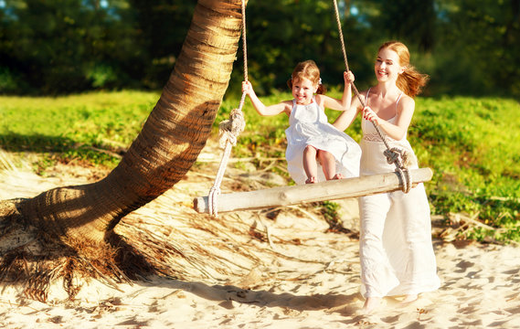 happy family at beach. mother shook child on swing in summer