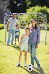 Obraz premium Smiling mother and daughter standing together at the park