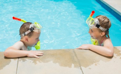 Boy and girl relaxing on the side of swimming pool