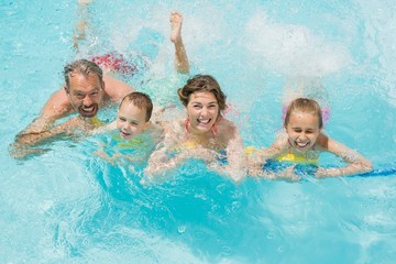 Happy parents and kids having fun in pool