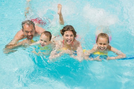 Happy parents and kids having fun in pool