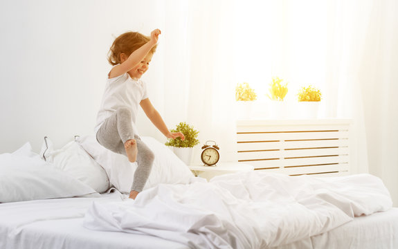 happy child girl  jumps and plays bed