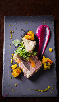 Slice of terrine with cauliflower and sauces on slate board