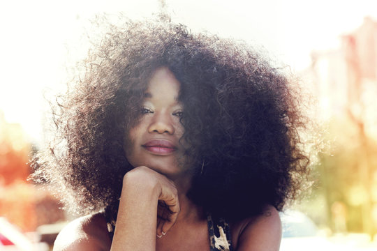 portrait jeune femme noire avec grande coiffure afro cheveux bouclés en ville en été