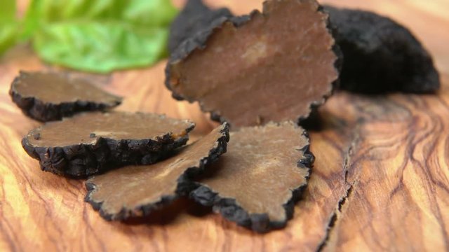 Thin slices and tubers of black truffle lying on a wooden board