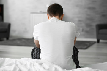 Handsome depressed man on bed at home