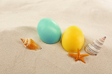 Colorful Easter eggs with seashells on sand