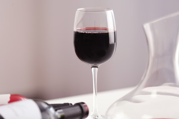 Wineglass and bottles of red wine on light background