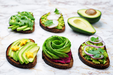 Variation of healthy rye breakfast sandwiches with avocado and toppings