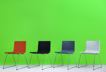 Fototapeta premium Modern chairs in a row on green wall background