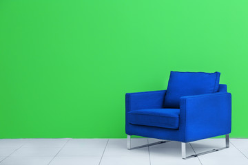Comfortable blue armchair on green wall background