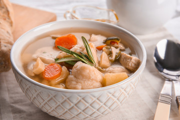 Bowl of delicious chicken and dumplings on dining table