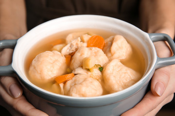 Female hands holding ceramic pan with delicious chicken and dumplings