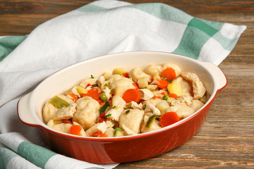 Baking dish with delicious chicken and dumplings on wooden table