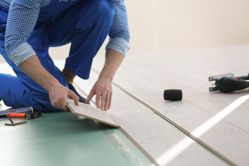 Male worker hands installing laminate flooring
