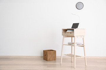 Stand-up desk with laptop near light wall