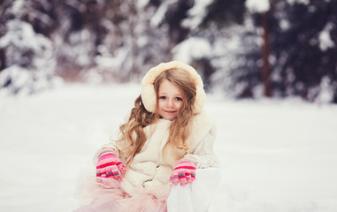 portrait of little girl in fur coat in snowy park