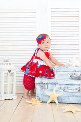 A little traveler sits on suitcases in a red dress.