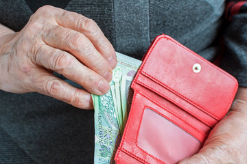 Hands of an elderly pensioner holding leather wallet with polish currency money. Concept of...