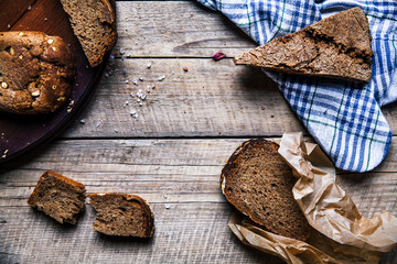 A loaf of fresh rustic wholemeal rye bread on a wooden board, rural food background.