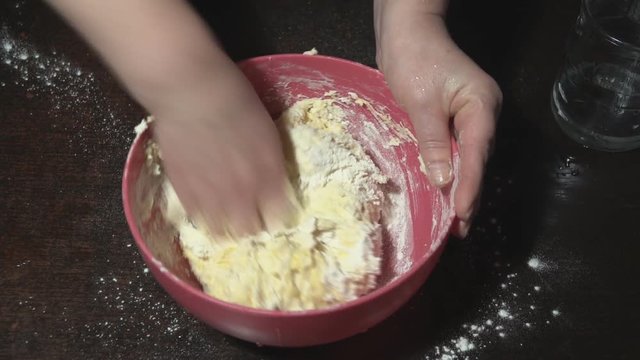 Female hands knead the dough in a bowl. Preparation of dough for dumplings. Traditional Ukrainian cuisine