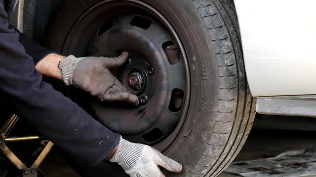Sc&egrave;ne de montage d'une roue de voiture