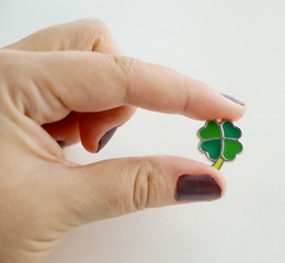 Female hand holding a leaf clover charm on the white background