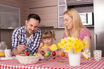 Happy Mother and Father with Kid Decorating Easter Eggs On Kitchen Table 