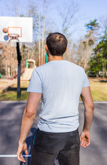 Back of young fit muscular man throwing basketball into hoop