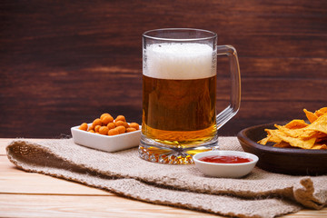 Glass of beer. Nachos chips. Tortilla snack. Mexican salsa nuts. Appetizer with sweet salsa or chilli sauce. Mug or pint of ale. On rustic wooden background.
