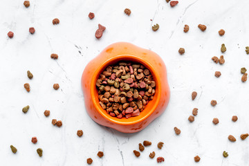 dry cat food in bowl on stone background top view