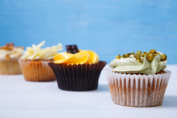 Cupcakes with buttercream. Sweet cake with pistachio cream and small chocolate bar. Dessert on blue wooden background.