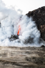 Fototapeta na wymiar Lava pours into Pacific ocean from lava tube, with steam, explosions and smoke