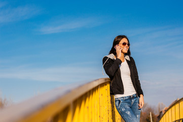 Young pretty woman talking at cellular phone on  bridge