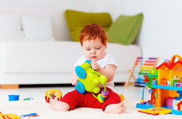 cute infant redhead baby playing with toys at home