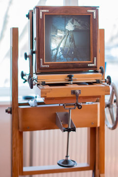 An ancient vintage wooden camera in front of the window, on the screen you can see a projection of nature
