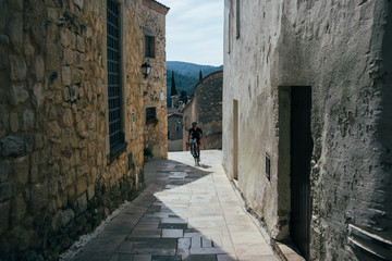 Cyclist riding between pave road in a village in spain