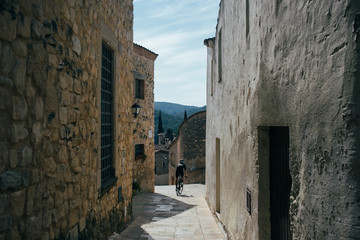 Cyclist riding between tight stone roads in a small village in spain