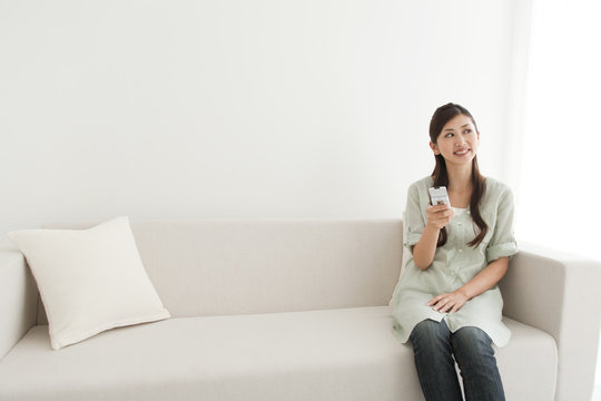 Young woman holding mobile phone on sofa
