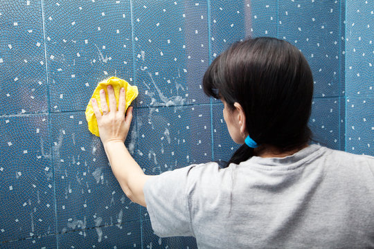 Woman Cleaning Bathroom Tiles