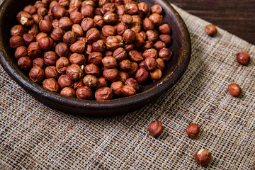 Hazelnut in bowl. Peeled nuts. Organic food on rustic wooden table with sackcloth. Top view.
