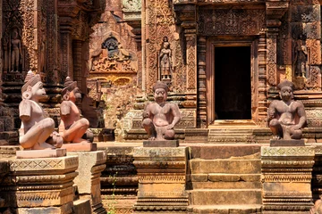 Wall murals Monument Banteay Srei temple, Angkor, Cambodia. Statues of human figures with animal heads, guardians at the ancient Khmer temple built in red sandstone