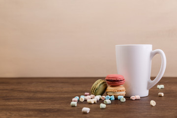 Macaroon cakes with colorful fluffy marshmallows. Mockup white tea cup. Almond sweet cookies. Wooden rustic board.