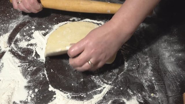 Female hands roll out the dough on the table. Preparation of dough for dumplings. Traditional Ukrainian cuisine