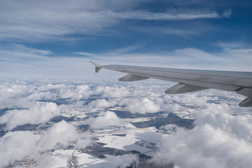 Flying above clouds. Wing of airliner and groups of clouds beneath.