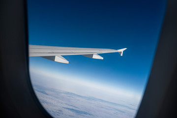 Wing in window in front of bright blue sky in stratosphere