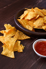 Nachos chips. Delicious salty tortilla with sweet salsa or chilli sauce on wooden background. Snack on rustic plate.