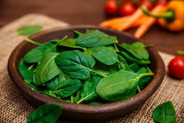 Spinach leaves in bowl. Raw fresh vegetable. Fresh natural plant leaf. Organic bio food on rustic wooden table.